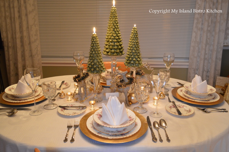 A Christmas Table set with formal china, 3 green tree candles and a collection of reindeer