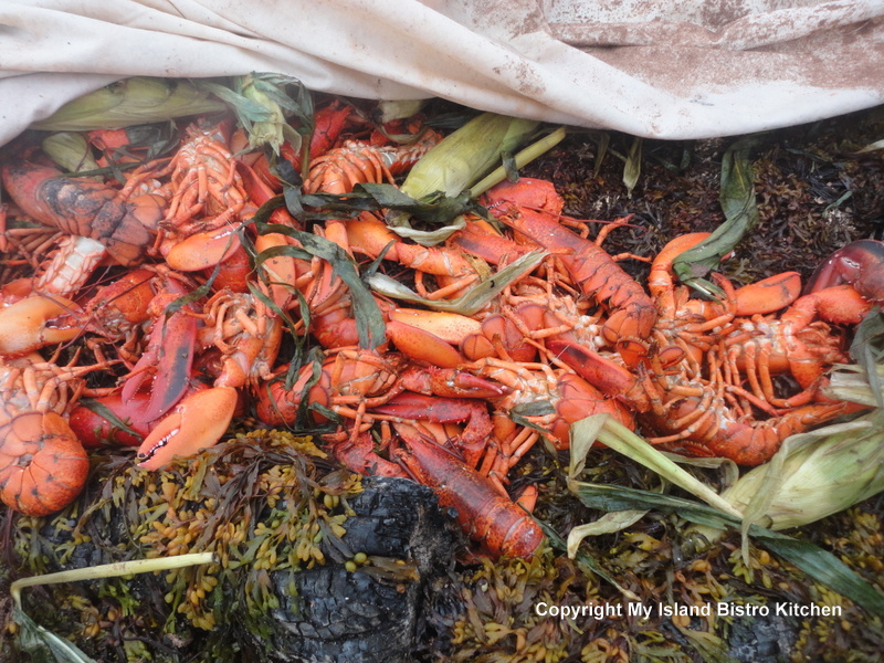 PEI lobsters and corn on the cob being cooked in a sandpit on the beach