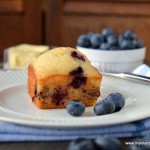 Blueberry Muffin on white plate surrounded by fresh blueberries