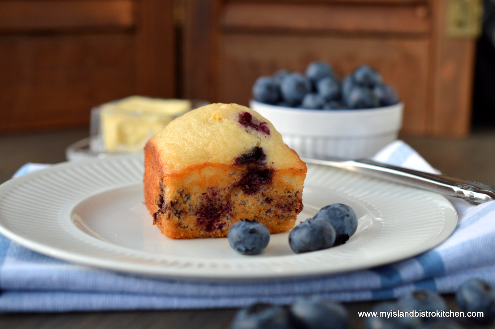 Blueberry Muffin on white plate surrounded by fresh blueberries