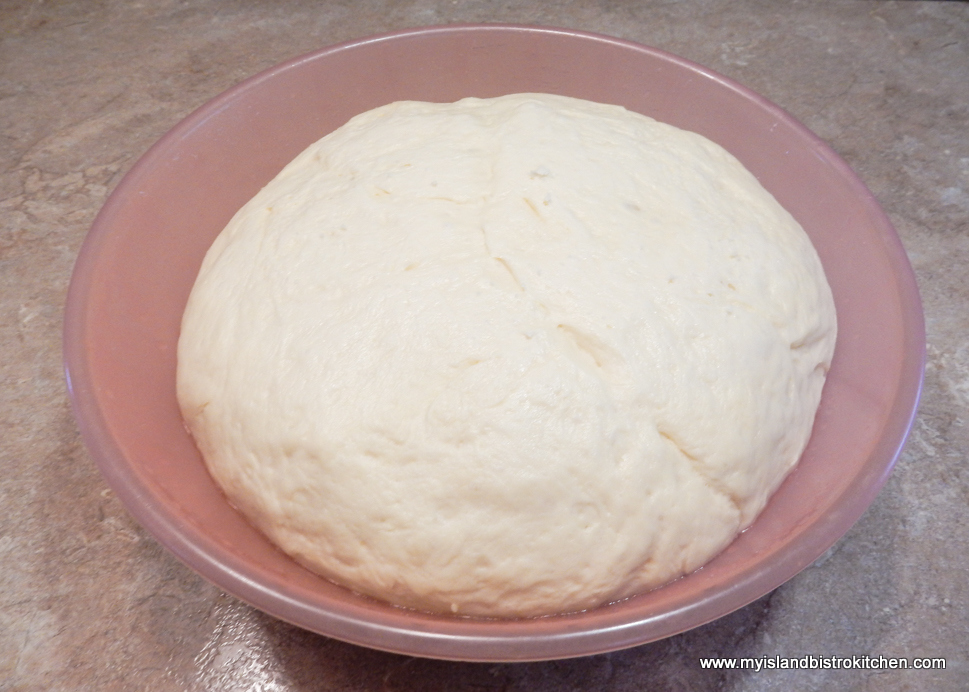 Risen yeast roll dough inside pink bowl