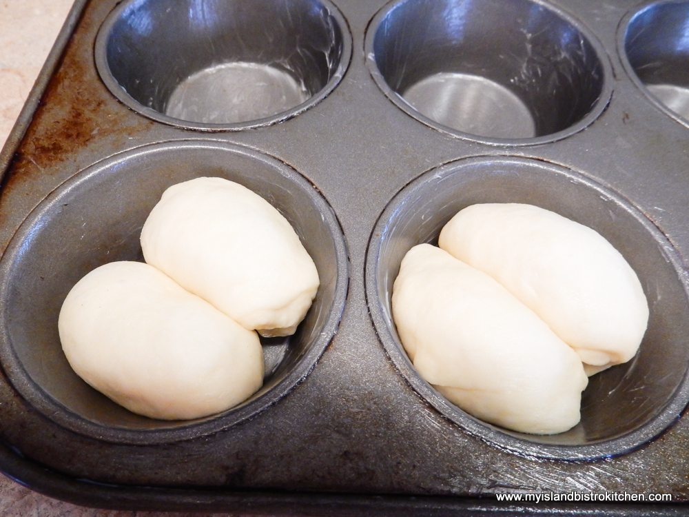 Two oval-shaped pieces of yeast dough placed in muffin cup