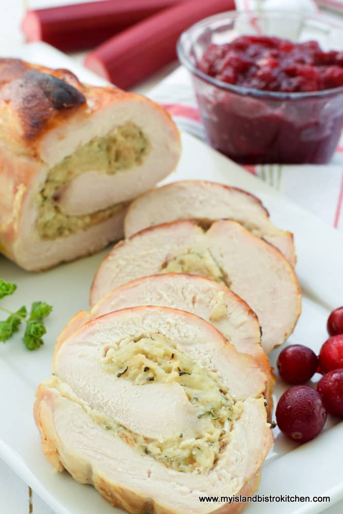Slices of rolled stuffed turkey breast with small glass bowl of Cranberry Rhubarb Sauce