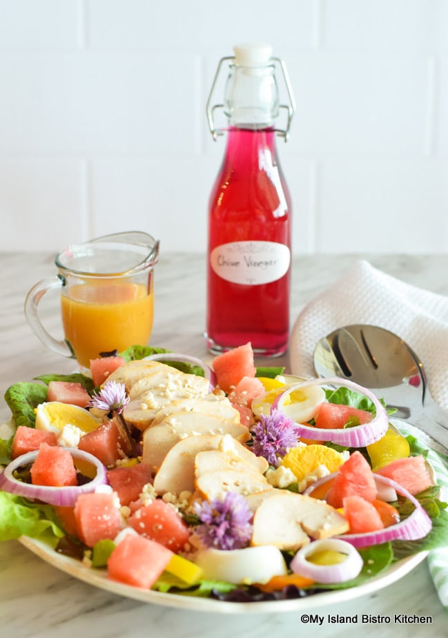 Plate of Salad with Bottle of Chive Vinegar and Small Jug of Vinaigrette in background