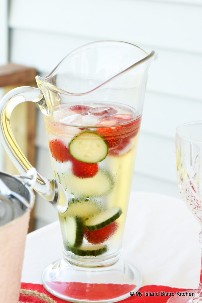 Water Jug filled with water infused with strawberries and cucumber