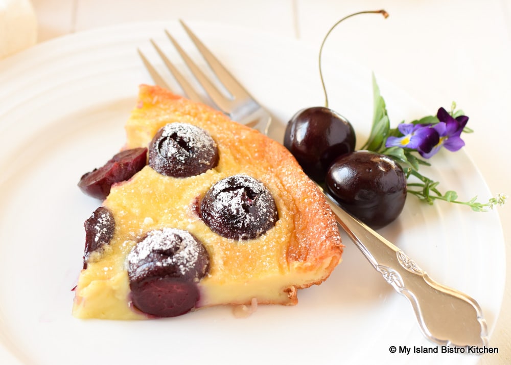 Slice of Cherry Clafoutis garnished with fresh cherries