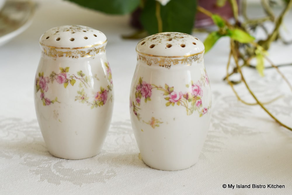 Antique salt and pepper set with tiny pink flowers on a white background