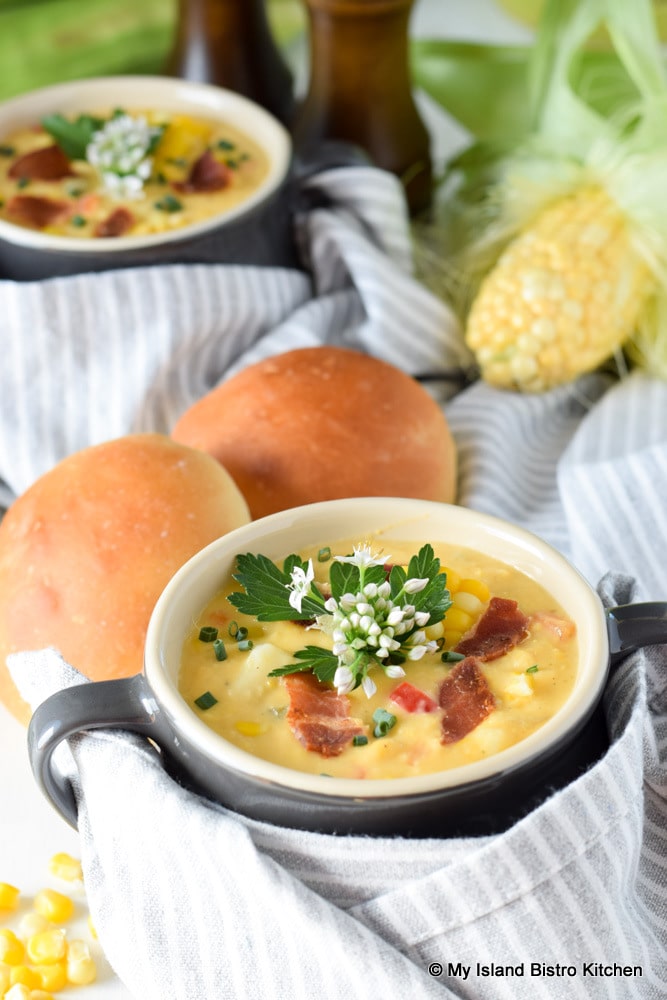 Bowl of corn chowder with two homemade rolls