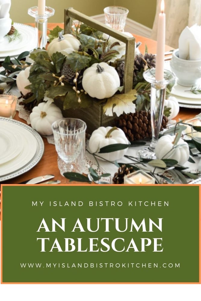 Miniature white pumpkins, muted shades of greenery, and pinecones are the focus of this stylish autumn tablesetting