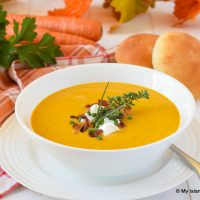 Bowl of Cream of Carrot Soup served with homemade rolls