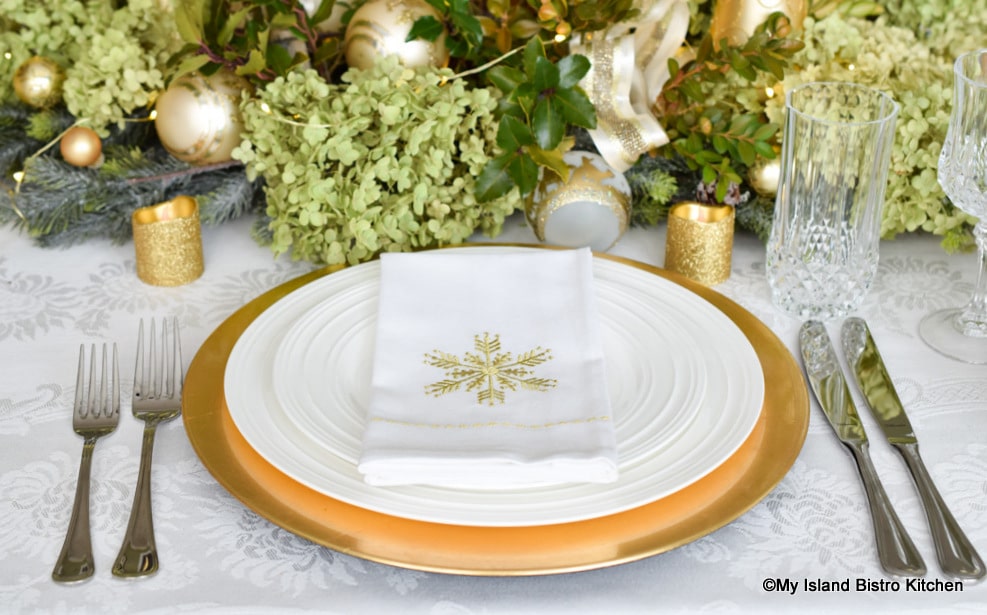 Placesetting of white plate on gold charger plate