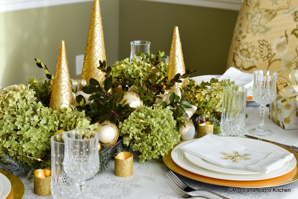 Gold trees, dried hydrangea, and holly leaves form a neutral holiday tablesetting