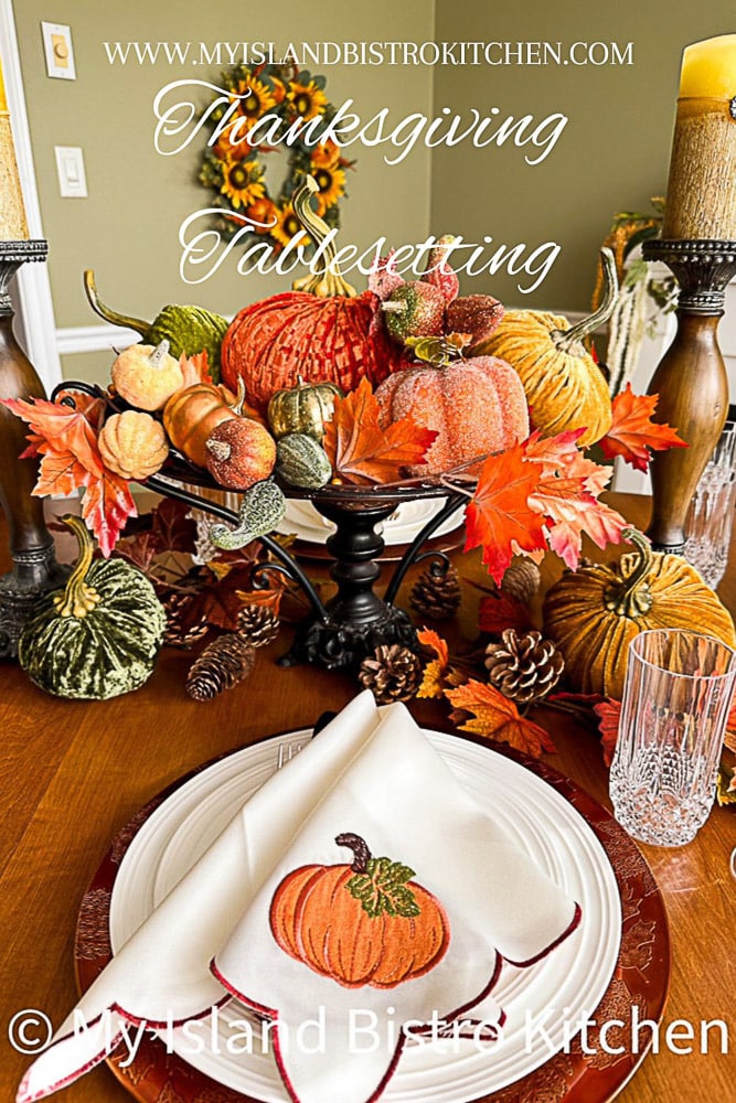 A Thanksgiving themed tablesetting with a variety of pumpkins in different colors, textures, and shapes nestled amongst colored leaves and pine cones.