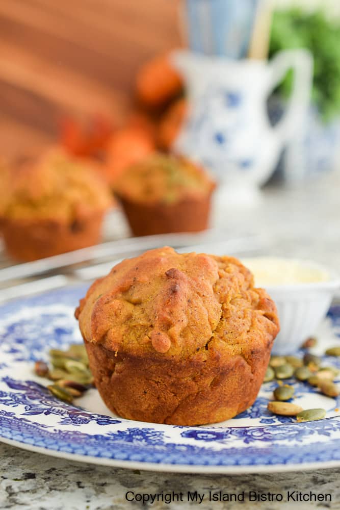 Pumpkin Muffin on blue floral plate with several muffins on cooling rack in background