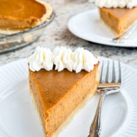 Slice of Sweet Potato Pie on white plate with pie in background