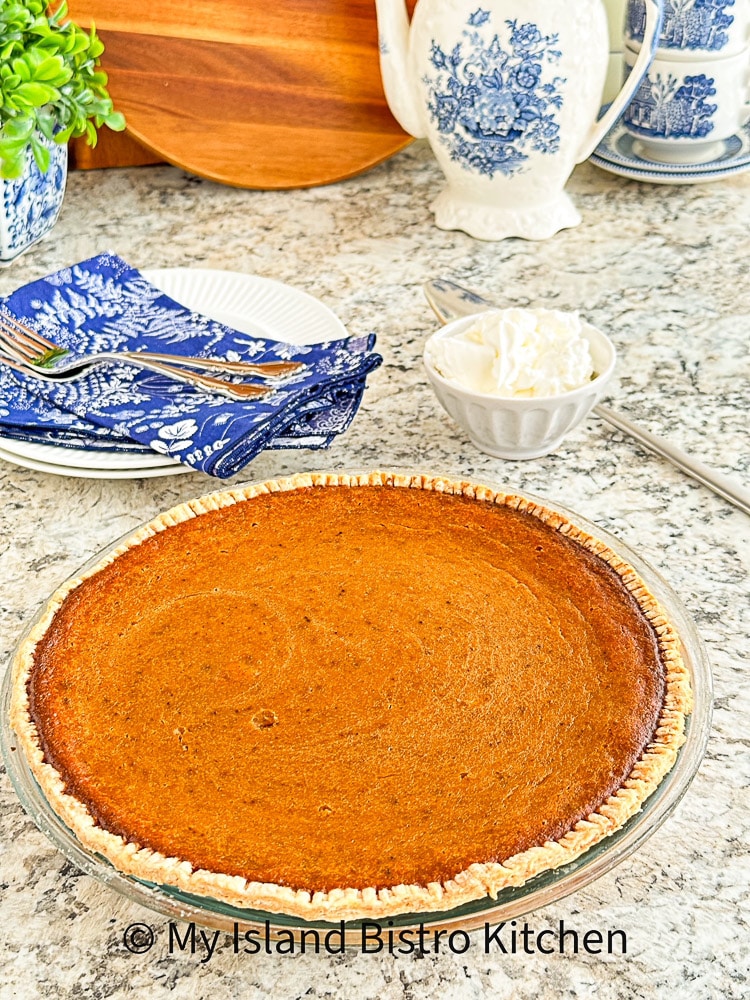 Sweet Potato Pie with whipped cream, plates, napkins, forks, teapot, and cups and saucers in background