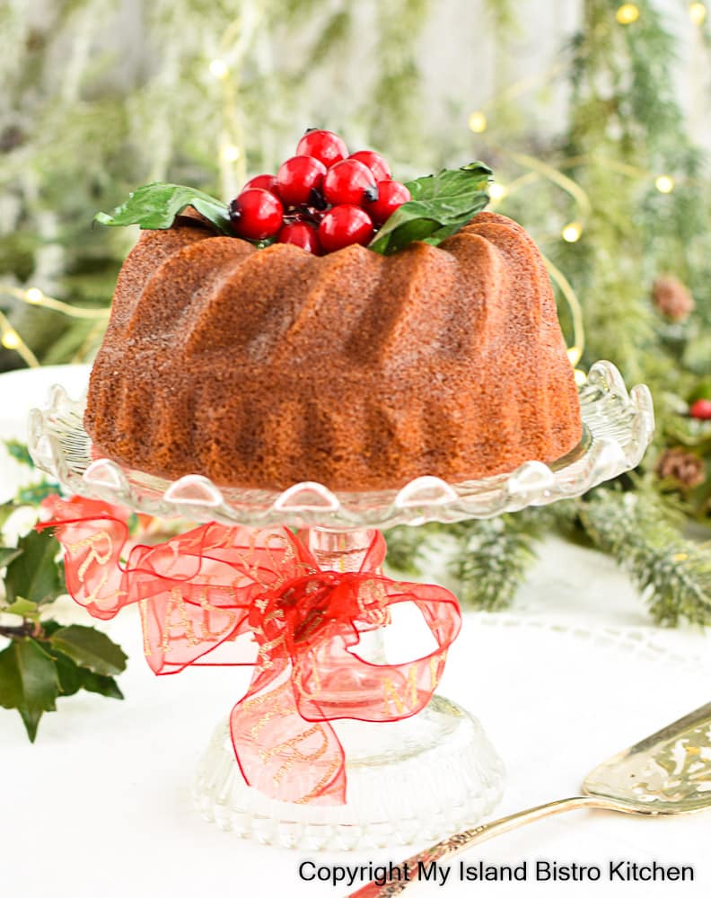 Cake sits on a glass pedestal dish decorated with red Christmas ribbon
