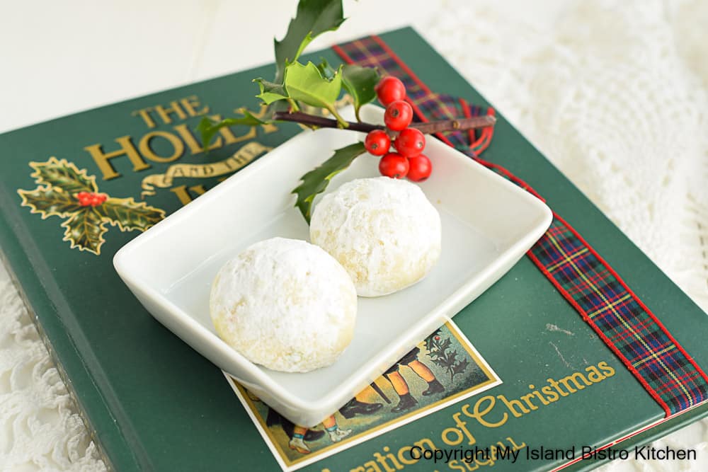 Mexican Wedding Cookies in small white dish atop a green Christmas book