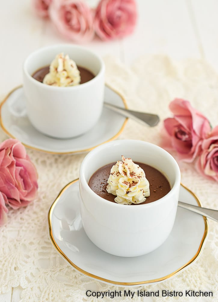 Two small white pots of chocolate custard set amidst pink roses