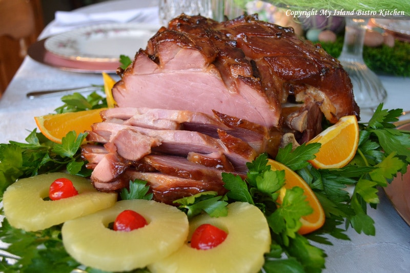 Baked Ham surrounded by pineapple slices on bed of greens