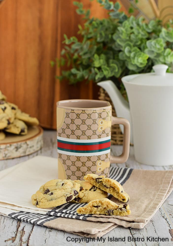 A pot of tea and mug form the background for cookies made with chocolate chips