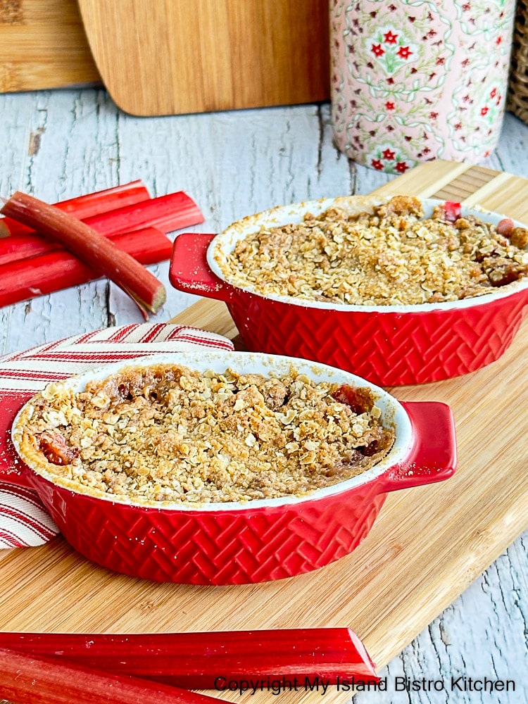 Fruit Crisp served in individual baking dishes. Stalks of rhubarb appear in the background