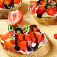 Crostini topped with sliced strawberries and balsamic reduction