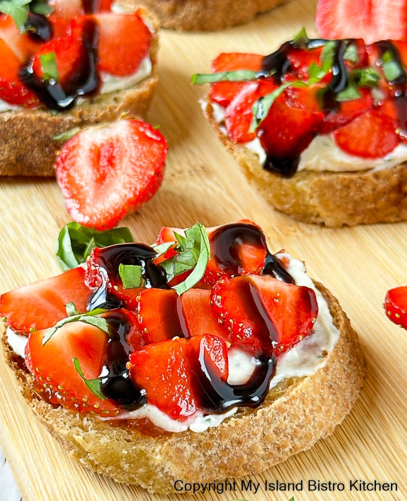 Crostini topped with sliced strawberries and balsamic reduction