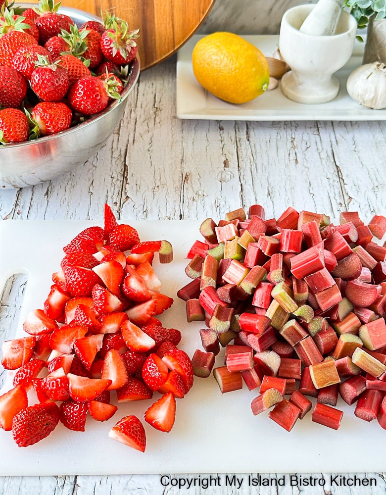 Chopped strawberries and rhubarb on white cutting board