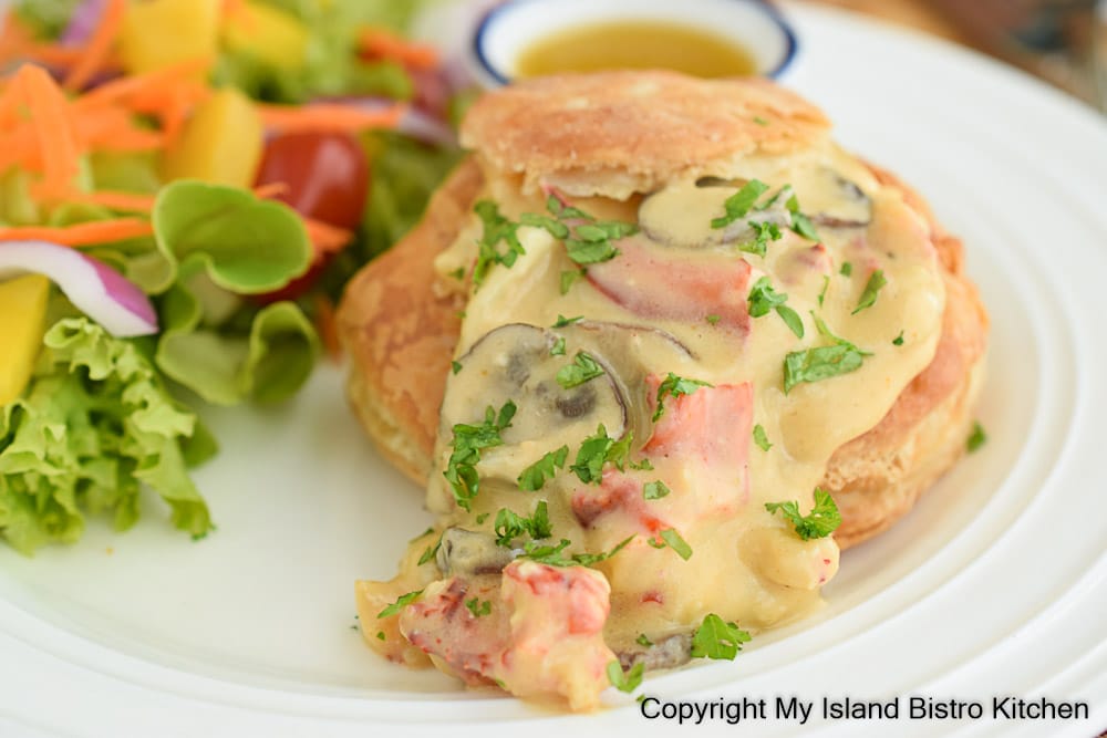 Lobster in cream sauce served in patty shells alongside a colorful mixed green salad