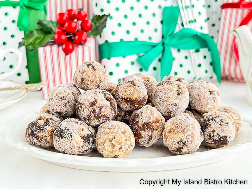 White plate filled with date and nut balls sits in front of colorful Christmas packages in background