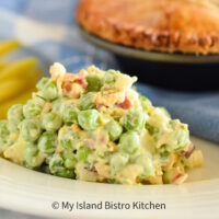 A summer side salad made with fresh peas, hard-boiled eggs, crispy bacon, red onion, cheese, and celery