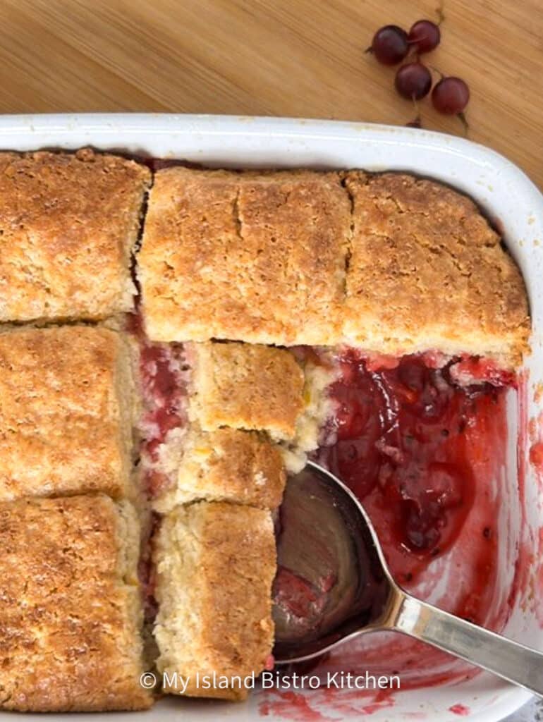 A cobbler made with gooseberries in white casserole dish