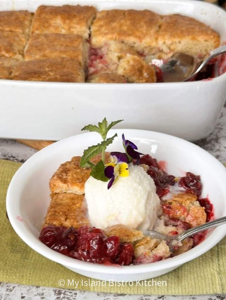 A white bowl filled with a gooseberry filling and topped with a biscuit topping