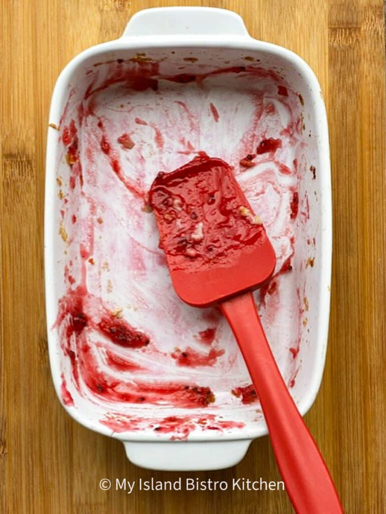 A red spatula sits in an empty casserole dish that contained Gooseberry Cobbler. Good to the last scraping of the baking dish!