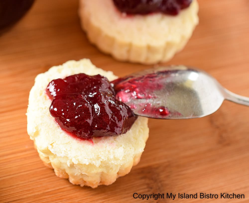 Close-up photo of a biscuit topped with dark red plum jam