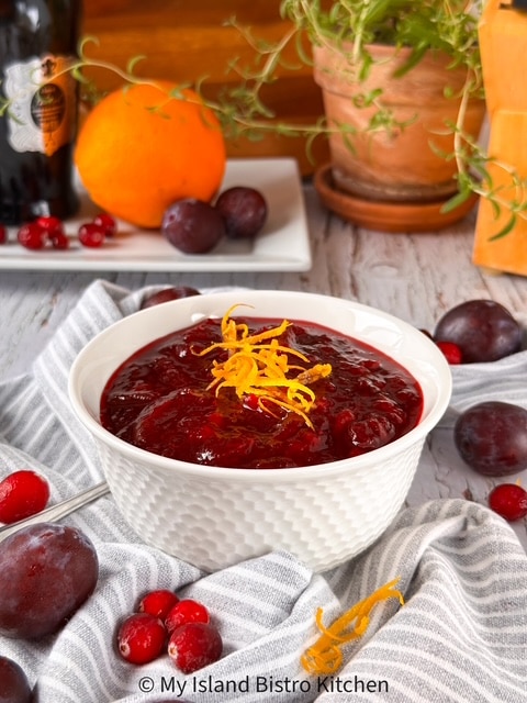 White bowl filled with homemade cranberry sauce garnished with orange slivers
